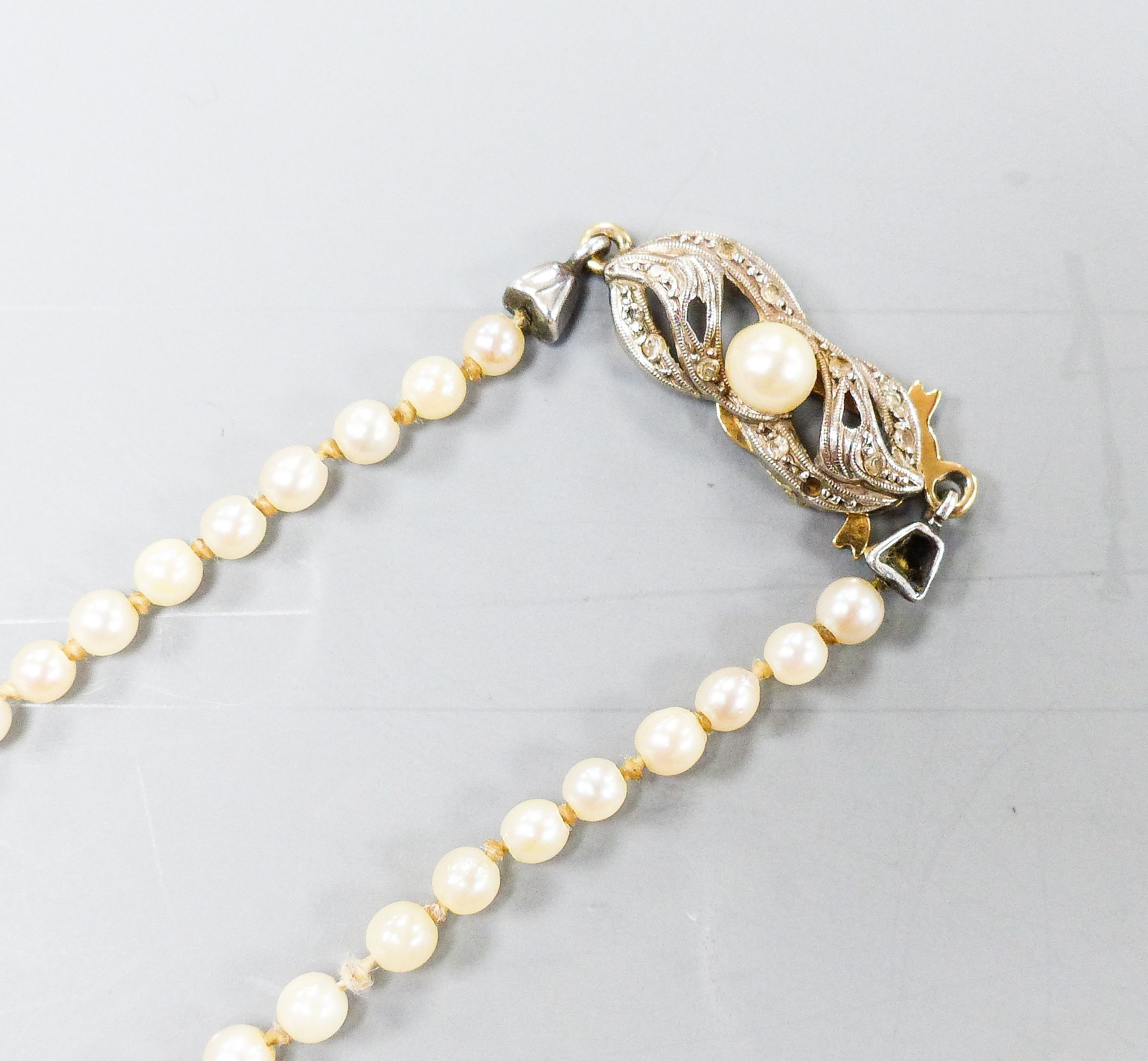 A single strand graduated cultured pearl necklace with yellow metal and gem set clasp, 49cm.